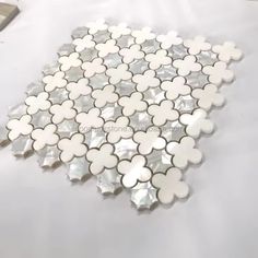 white and silver flower shaped glass mosaic tiles on a table with other items in the background