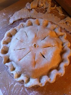 an uncooked pie sitting on top of a wooden table next to another pie