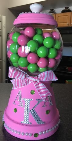 a pink gum ball machine with green and pink candies in it's top