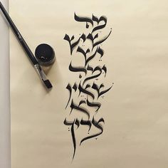 an artistic calligraphy work done in black ink on white paper with a brush next to it