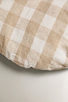 a white and brown checkered pillow on top of a table