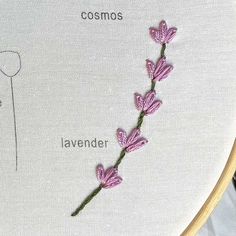 a close up of a cross stitch on a piece of cloth with the words cosmos lavender