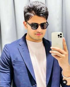 a man in sunglasses is taking a selfie with his cell phone while wearing a blue blazer