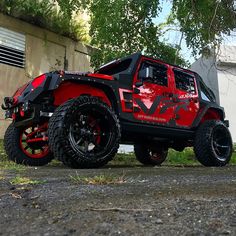 a red and black jeep parked in front of a building