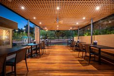 an outdoor dining area with tables and chairs under a pergolated roof at night