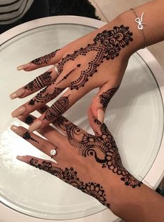 two hands with henna tattoos on them