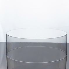 a clear glass vase sitting on top of a gray table next to a white wall