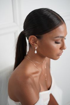 a woman wearing a white top and earrings