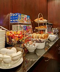 an assortment of food is displayed on the counter in this hotel breakfast buffet area, along with coffee and pastries