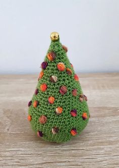 a small crocheted christmas tree sitting on top of a wooden table