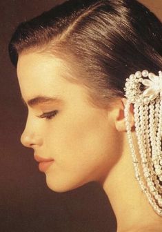 a close up of a woman wearing pearls in her hair