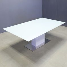 a white rectangular table sitting on top of a tile floor in an empty room with blue walls