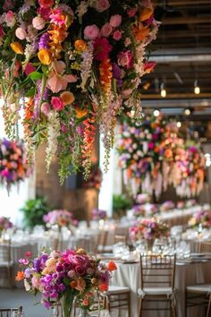 an arrangement of flowers hanging from the ceiling in a banquet hall with tables and chairs