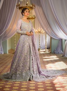 a woman standing in front of a chandelier wearing a purple gown and veil