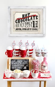 a red and white table topped with cups filled with hot chocolate next to a sign