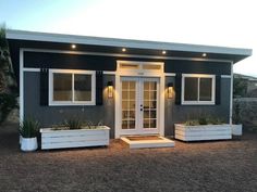 a small gray and white house with two planters