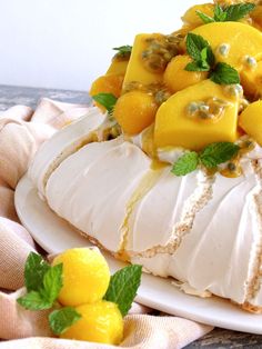 a cake with lemons and mint on top is sitting on a white plate next to two lemons