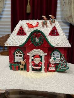 a red and green christmas house on a table