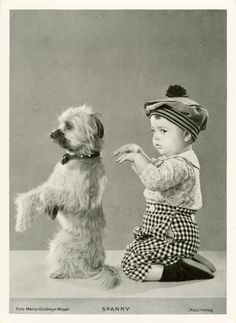 an old photo of a baby playing with a dog