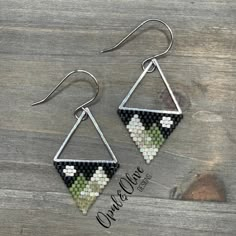 the earrings are made out of black and white mosaic tiles, with silver triangles hanging from them