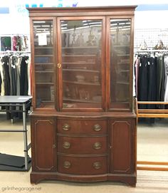 an antique china cabinet with glass doors in a clothing store or department showroom for men's and women's wear