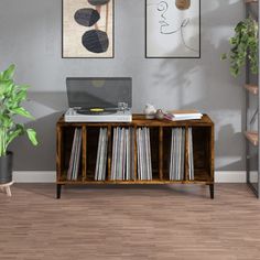 a record player sitting on top of a wooden table next to a plant and laptop computer