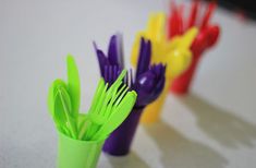 colorful plastic utensils lined up in a row on a table with white surface