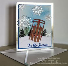 a christmas card with snowflakes and a sled in the background that says it's the season