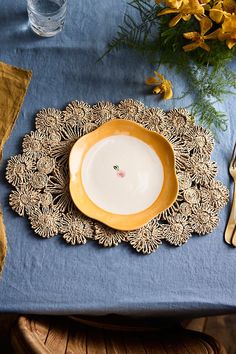 a yellow and white plate sitting on top of a blue table cloth next to silverware