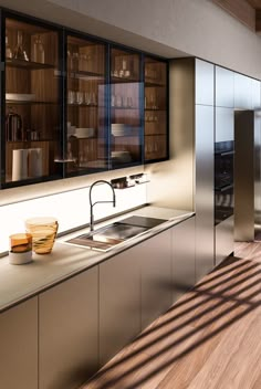 On the backsplash is the K Panel, which illuminates the counter space and is fitted to store small frequently-used items. On the left, the tall units incorporate pivot doors that hide the wet kitchen or pantry area. Aluminum Kitchen Cabinets, Wet Kitchen, Metal Kitchen Cabinets, Tall Kitchen Cabinets, Dry Kitchen, Glass Kitchen Cabinets, Modern Pantry, Aluminium Kitchen