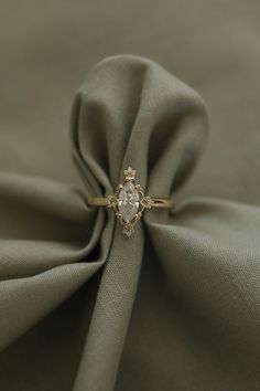 an engagement ring is sitting on top of a green satin material with a diamond center