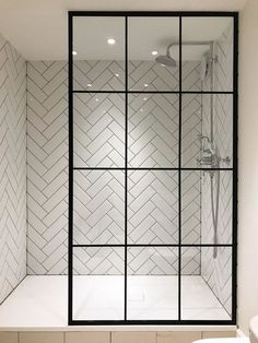 a bathroom with white tile and black trim on the shower wall, along with a toilet