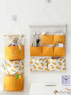 two orange storage bins are hanging on the wall next to a clock and other items