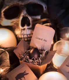 a box with an egg in it sitting next to candles and a skull head on the table