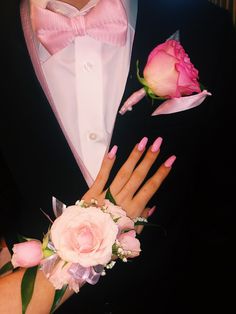 a man in a tuxedo with pink flowers on his wrist and two hands