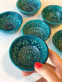 a hand is holding a blue bowl with four bowls in the shape of flowers on it