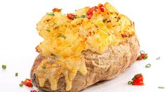 a baked potato with cheese and peppers on it's side, sitting on a white surface