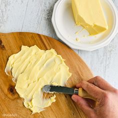 a person is cutting up some food on a wooden platter with a butter knife