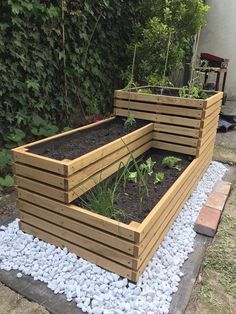 an outdoor garden area with raised wooden planters and graveled stones on the ground