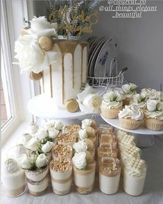 a table topped with lots of cupcakes covered in white frosting and flowers