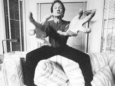 a man sitting on top of a couch with his hands in the air