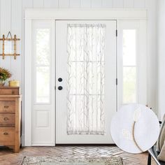 a white door with sheer curtains and a hat on the floor in front of it