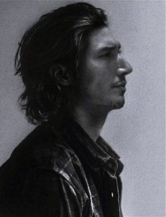 a black and white photo of a man with long hair looking off to the side