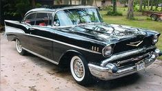 an old black car parked in front of a house