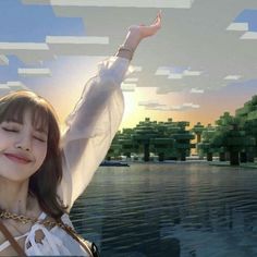 a girl with her arms outstretched in front of a lake and trees, while the sun is setting