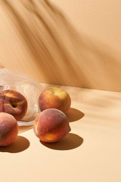 some peaches are sitting on a table next to a plastic bag with one peach in it