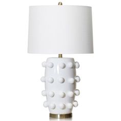 a white table lamp with dots on it and a light shade over the base that is turned off