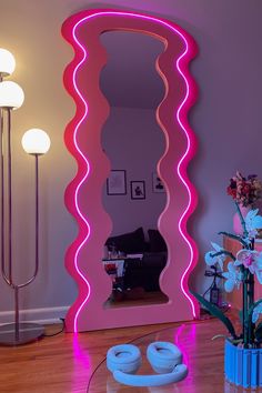 a large mirror sitting on top of a wooden floor next to a vase filled with flowers