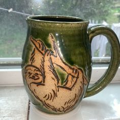 a green coffee mug sitting on top of a window sill