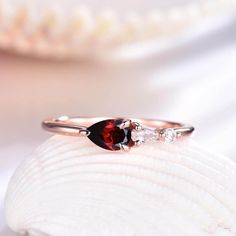 a close up view of a ring with a red stone on the side and two white stones